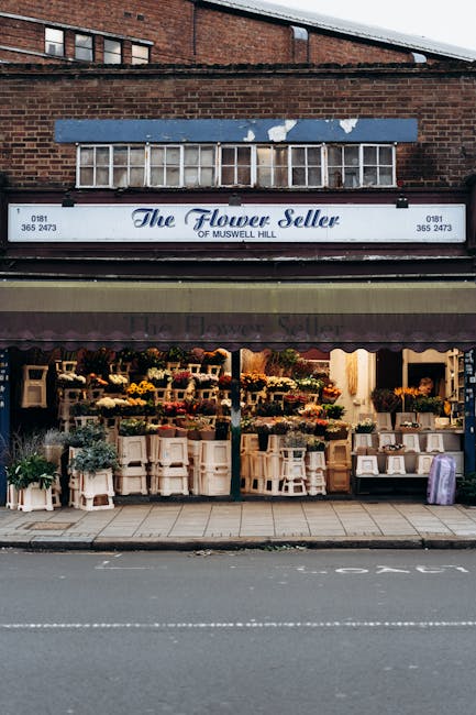 The exterior of The Flower Seller of Muswell Hill featuring a large storefront window displaying an array of fresh floral arrangements and bouquets. The display includes vibrant blooms such as yellow 